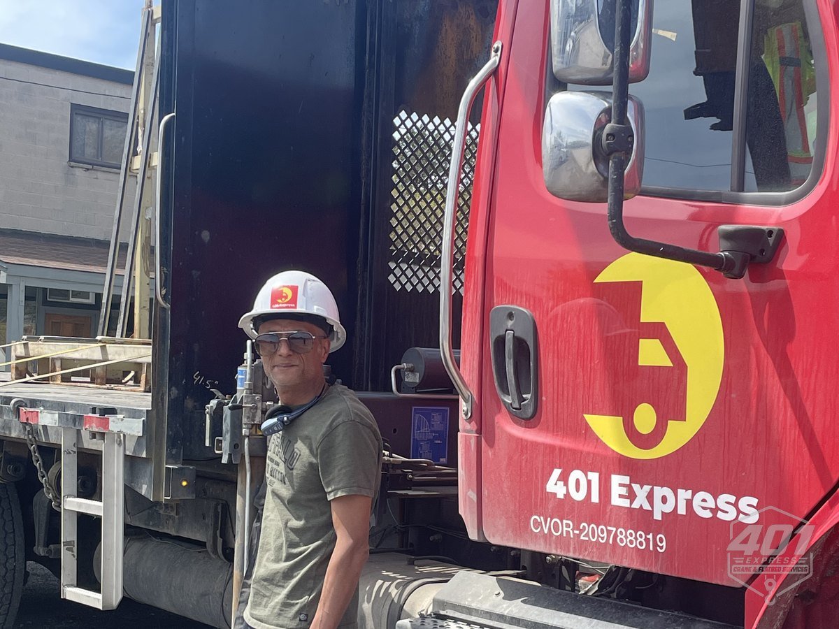 The owner-operator of 401 Express in a hard hat beside his crane truck in Toronto