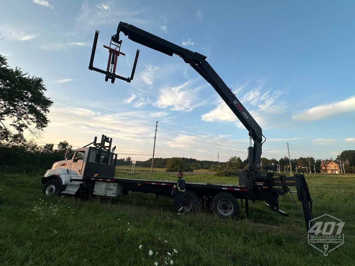401 Express boom truck with the crane fully extended and outriggers down at a job site in the GTA