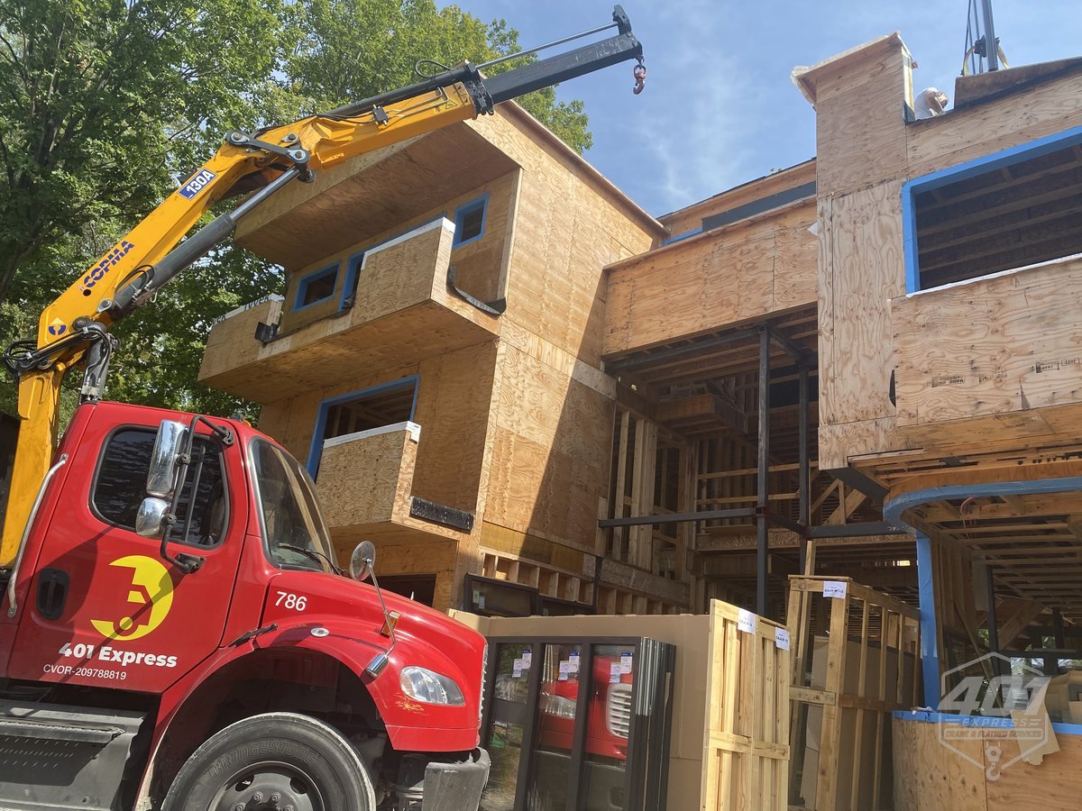 401 Express crane truck unloading framing lumber at a residential construction site in Toronto