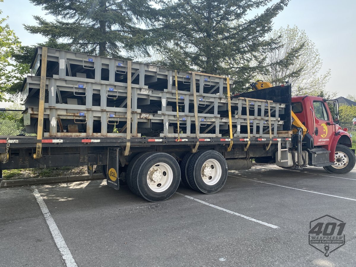 Stacked elevator frame components strapped to the 401 Express flatbed for transport across the GTA