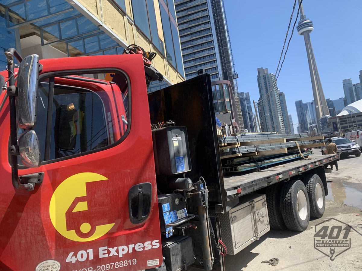 401 Express crane truck delivering elevator equipment beside a downtown Toronto high-rise