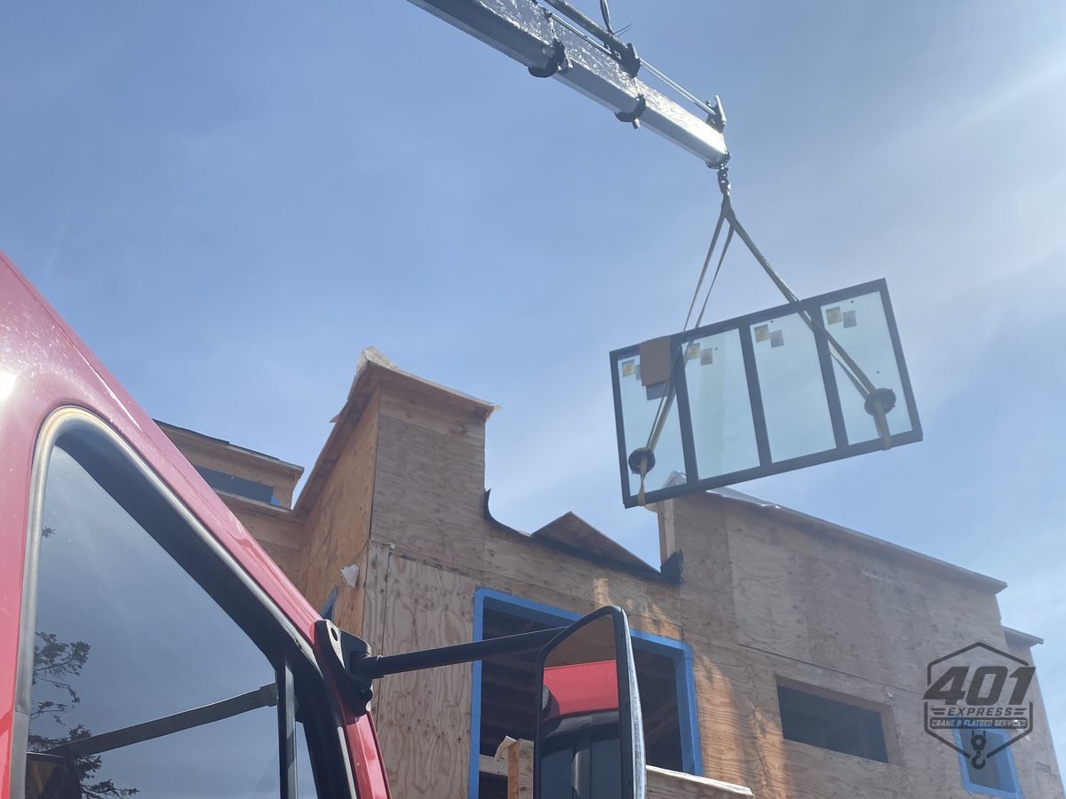 401 Express crane lifting a large glazed panel over a residential property in Toronto